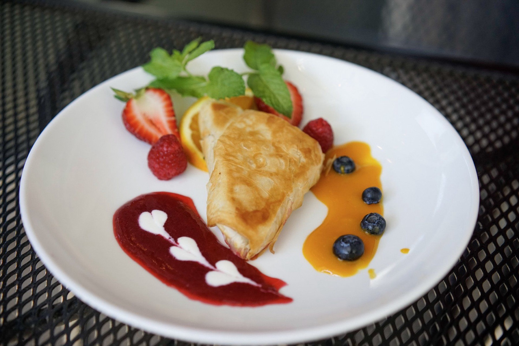 Baked brie in golden phyllo with raspberry and mango coulis, fresh berries and mint