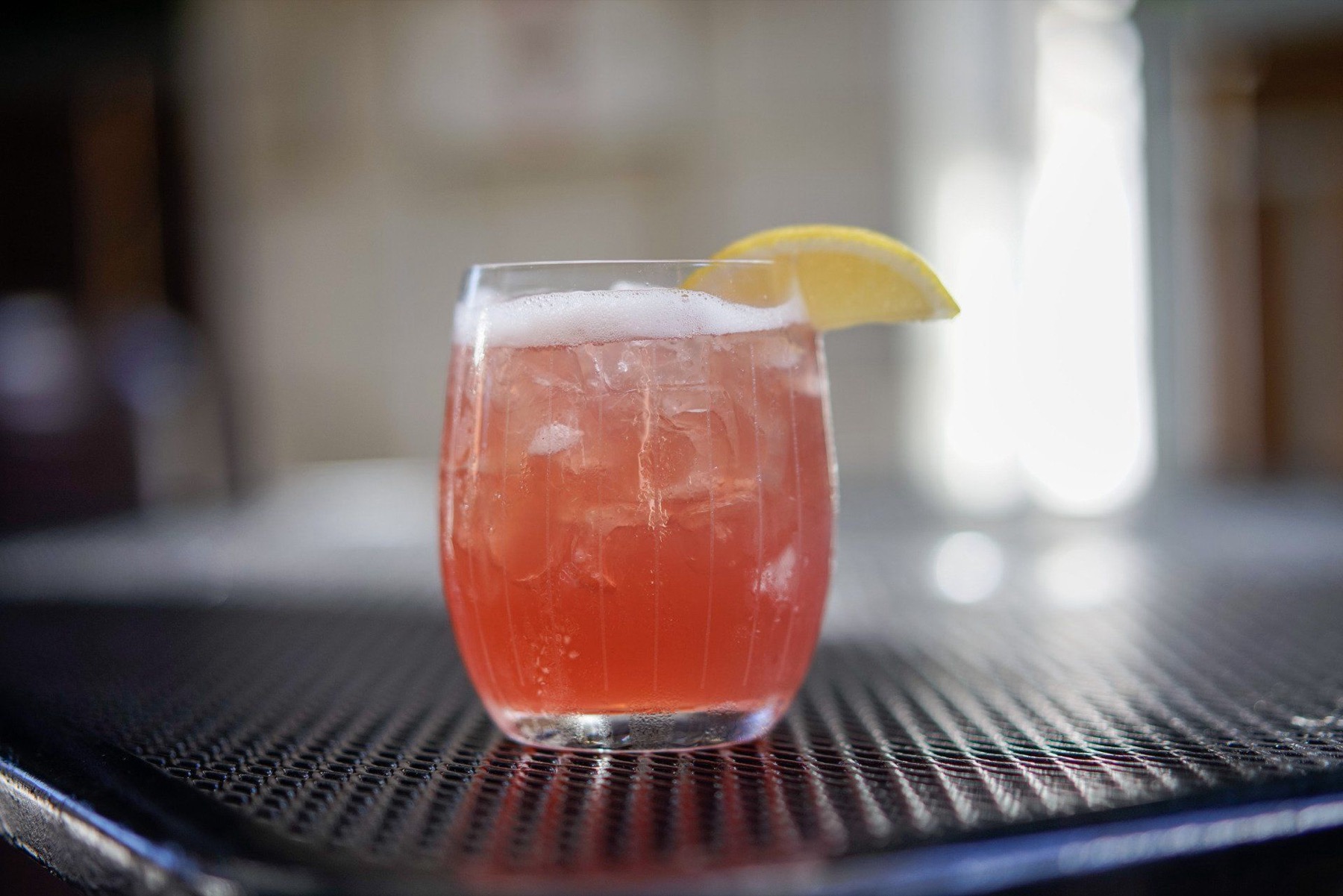 A ruby-red cocktail with a lemon wheel