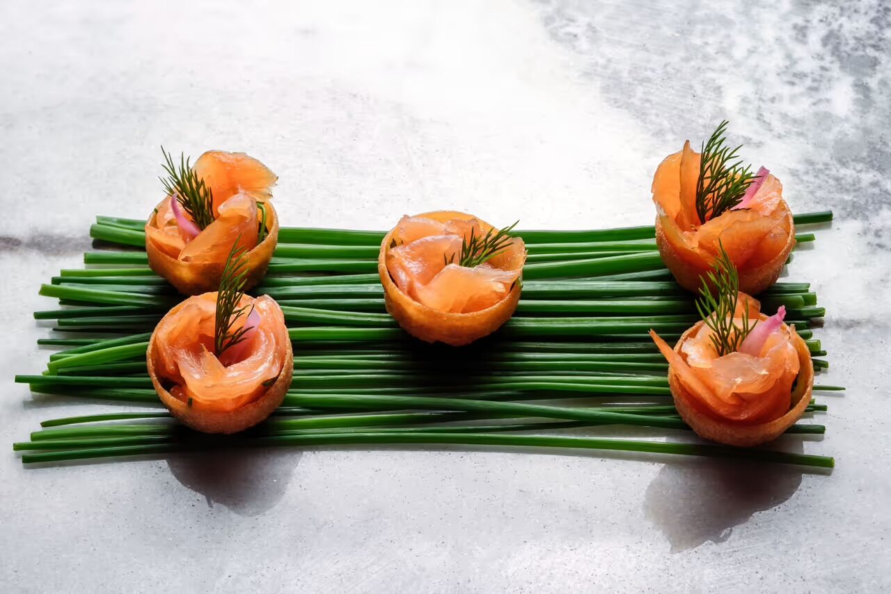 Smoked salmon canapés in tartlet shells over a bed of chives