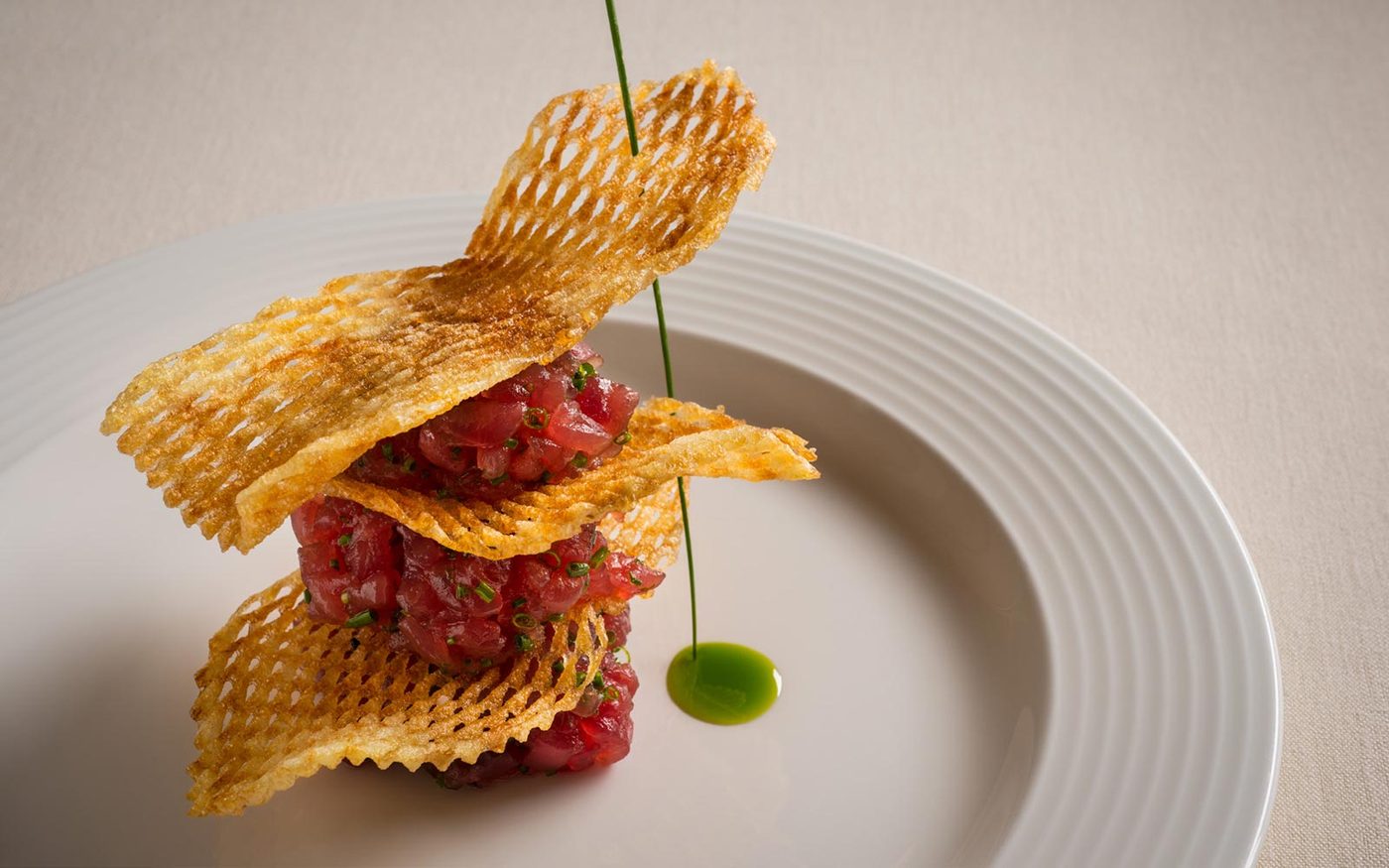 Tuna tartare tower layered with potato crisps and herb oil